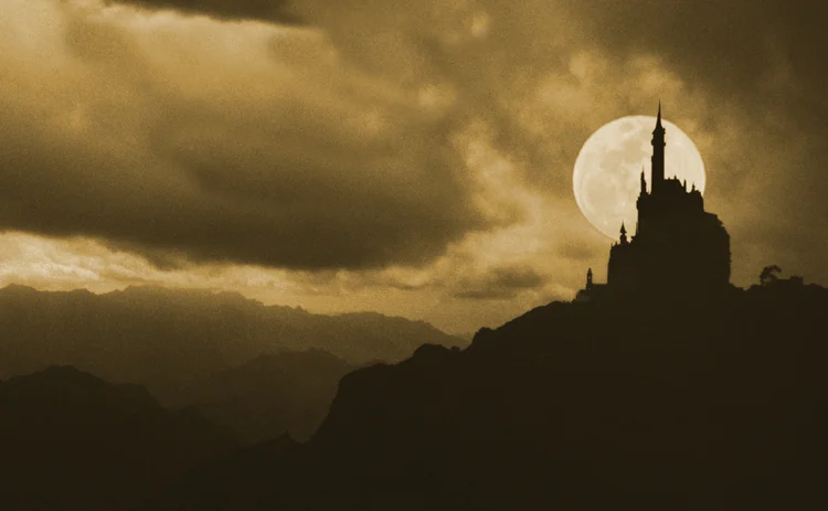 Silhouettes of a castle with full moon background behind it
