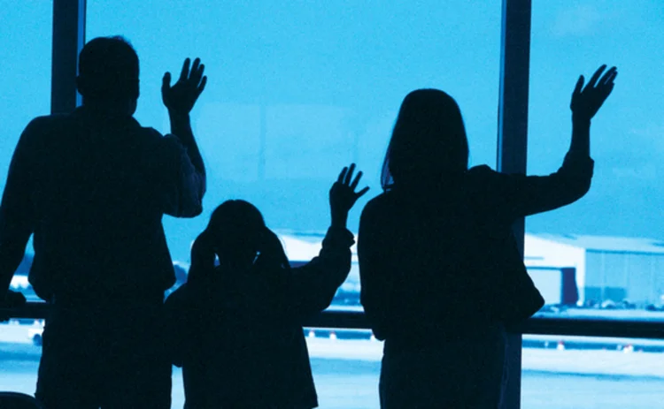 Family waving goodbye at an airport in silhouette