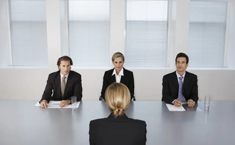 Photo of a woman facing a three-person interview panel
