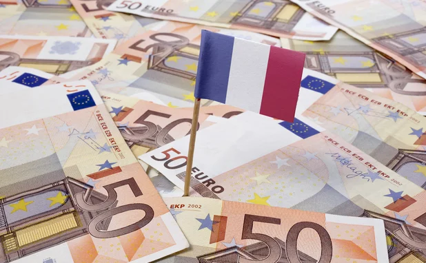 A pile of euro notes with a French flag planted in the middle