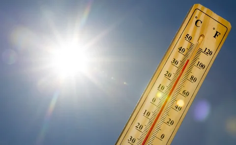 Mercury thermometer marking 39 degrees Celsius 100 Fahrenheit in a sunny day. Summer heat shown on mercury thermometer against the blue sky. Sunlight with sun flares.
