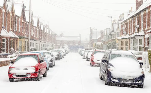 Looking along a typical UK town street covered in thick winter snow.