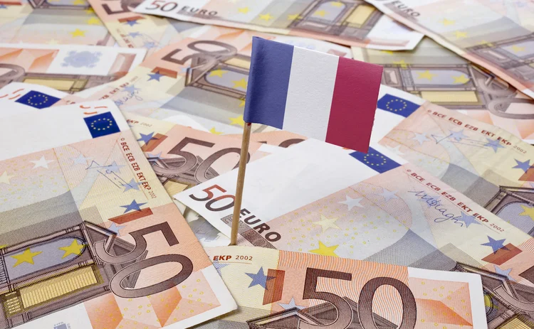 A pile of euro notes with a French flag planted in the middle