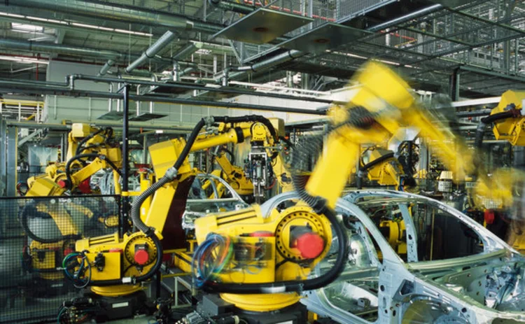 Yellow robots welding cars in a production line