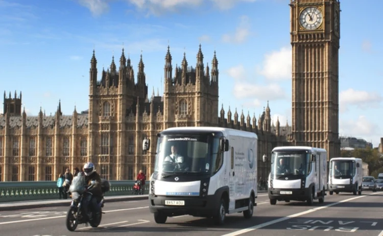 Modec electric vehicles driving past Parliament and Big Ben