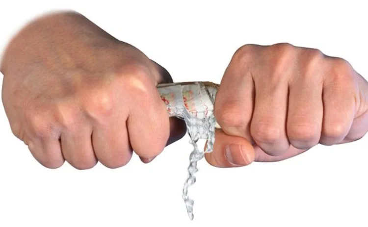 Twisting fifty pound notes between hands until water is wrung out