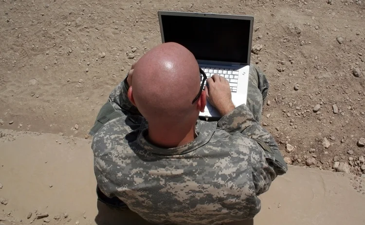 A Macbook being used by a person in military gear
