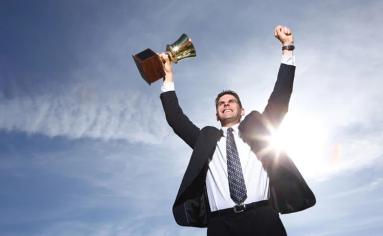 Businessman holding trophy aloft