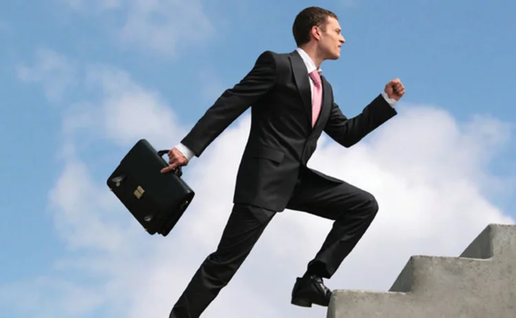 Businessman climbing staircase in the sky